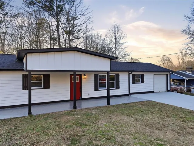 a front view of a house with a yard and trees
