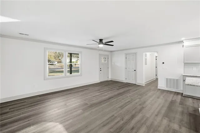 an empty room with wooden floor and windows