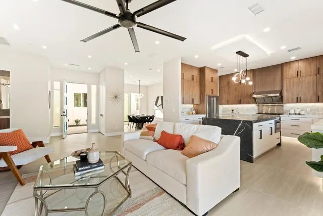 a kitchen with stainless steel appliances granite countertop a refrigerator a sink dishwasher a stove and a dining table with wooden floor