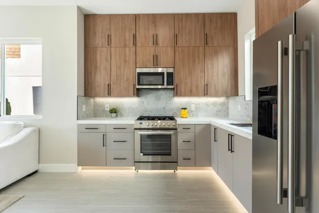 a open kitchen with stainless steel appliances granite countertop a stove top oven a sink dishwasher a dining table and chairs with wooden floor