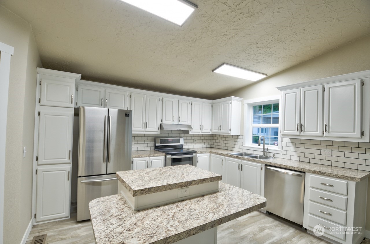 27 South Gee Creek Loop Ridgefield, WA 98642 - Photo 8 of 26 a kitchen with stainless steel appliances granite countertop a refrigerator sink and stove