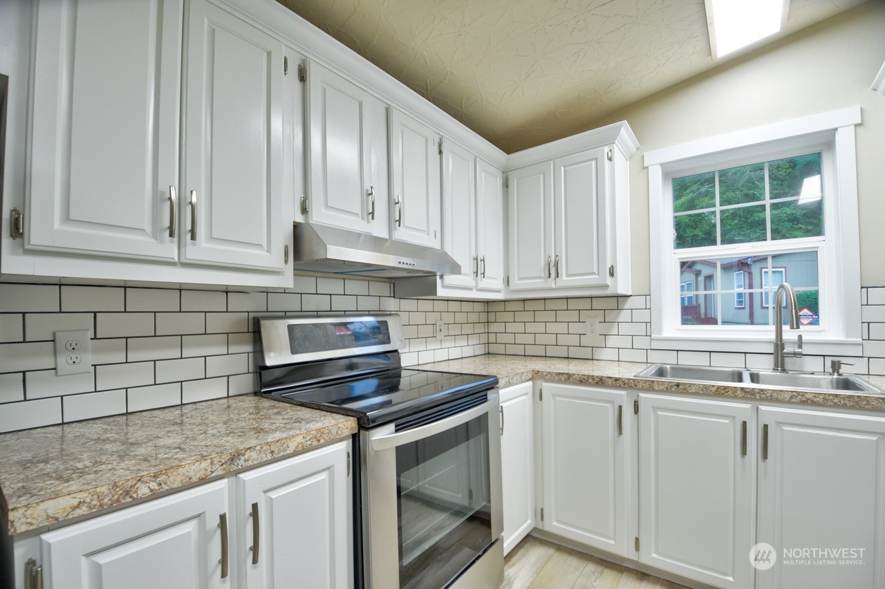 27 South Gee Creek Loop Ridgefield, WA 98642 - Photo 10 of 26 a kitchen with granite countertop a sink stainless steel appliances white cabinets and a window
