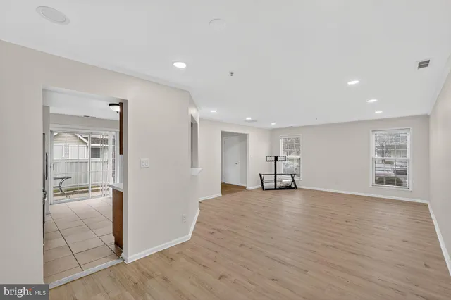 a view of an empty room with wooden floor and a bathroom