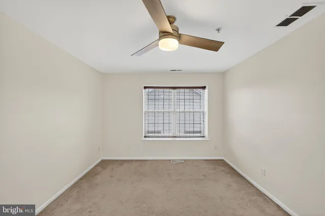 an empty room with a window and a ceiling fan