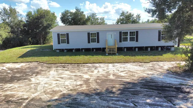a view of a yard in front of a house with large trees