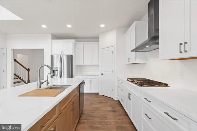 a large white kitchen with stainless steel appliances a sink and cabinets