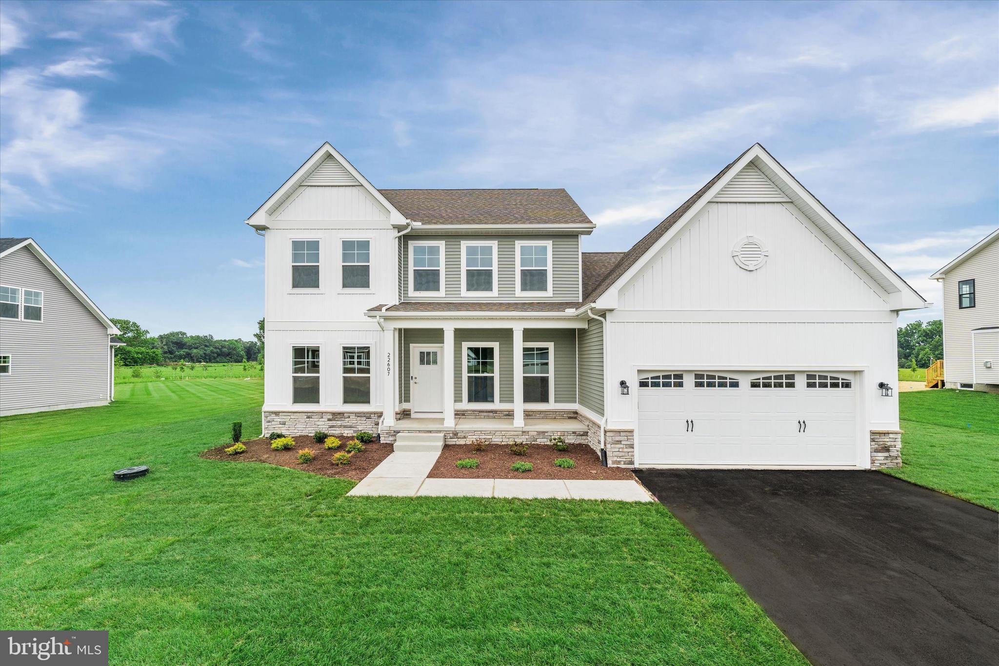 24025 Jerrico Road, Unit 38 Lincoln, DE 19960 - Photo 2 of 53 a view of a white house with a yard and table and chairs under an umbrella