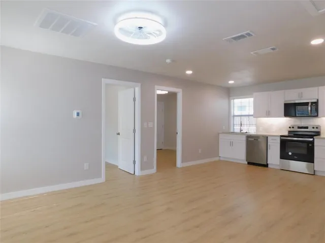 a view of a kitchen with a sink and dishwasher a refrigerator with wooden floor