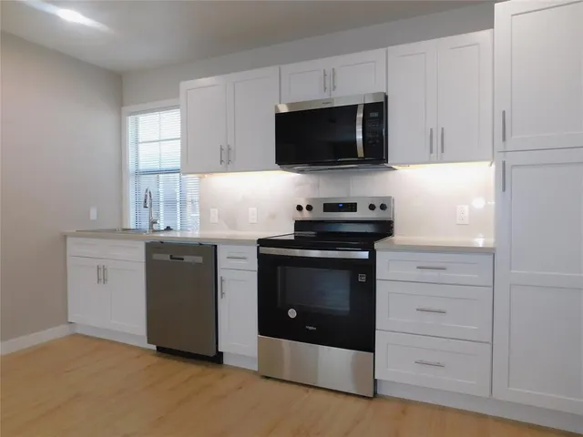 a kitchen with white cabinets and stainless steel appliances