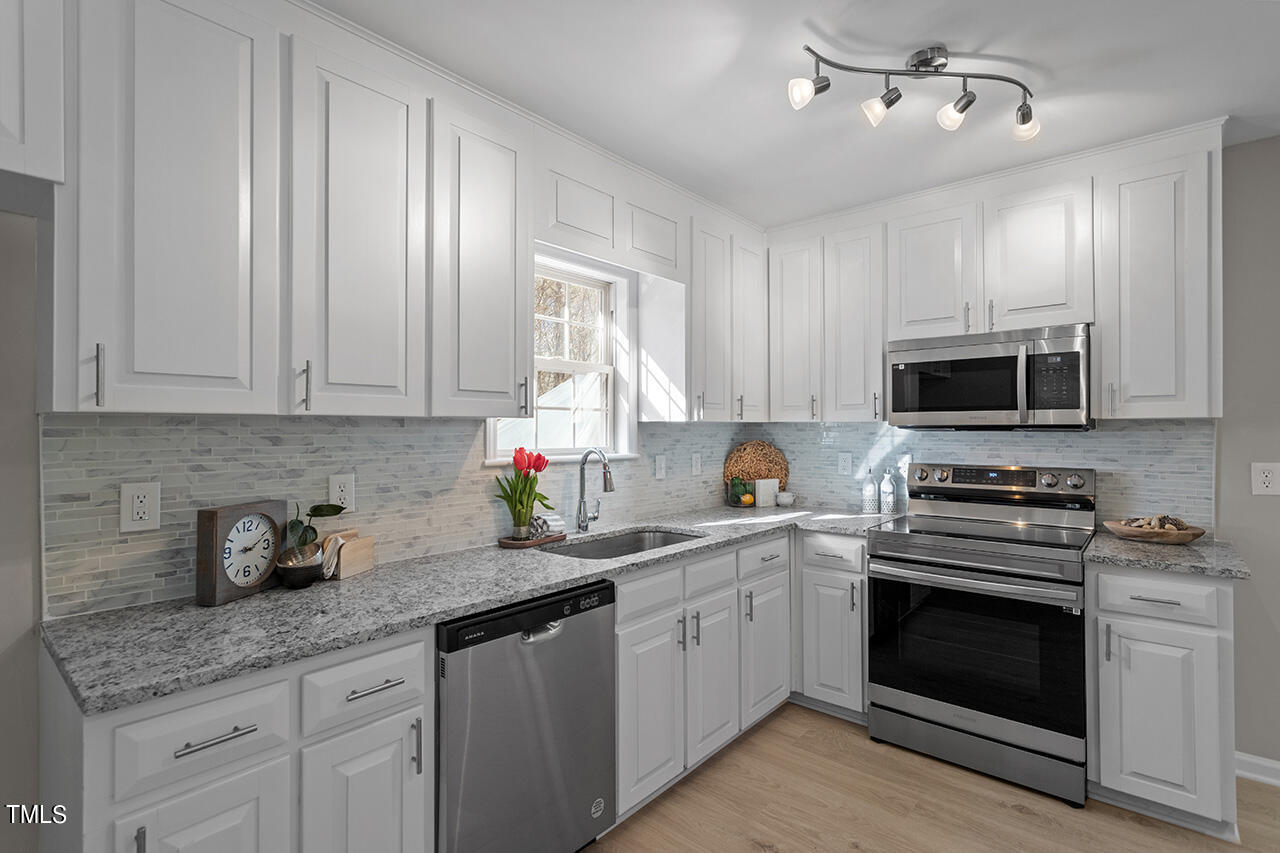 5404 Passenger Place Raleigh, NC 27603 - Photo 3 of 25 a kitchen with granite countertop white cabinets stainless steel appliances and sink
