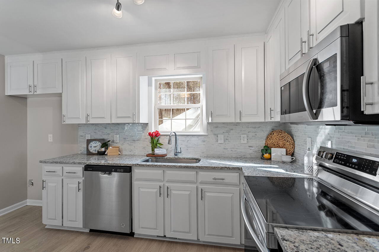 5404 Passenger Place Raleigh, NC 27603 - Photo 6 of 25 a kitchen with white cabinets stainless steel appliances and sink