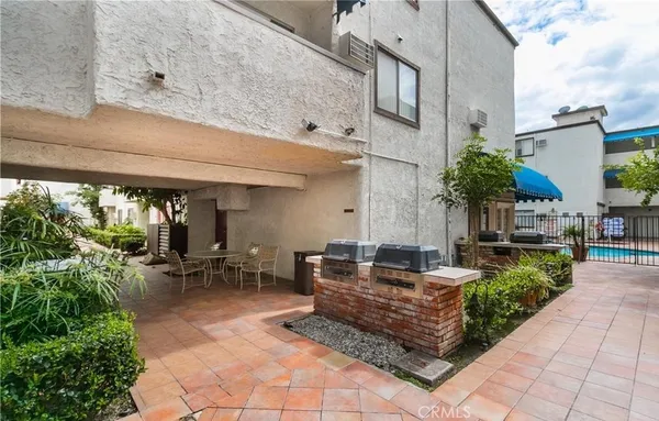 a view of a patio with table and chairs potted plants and floor to ceiling window
