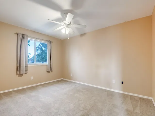an empty room with a window and a fan