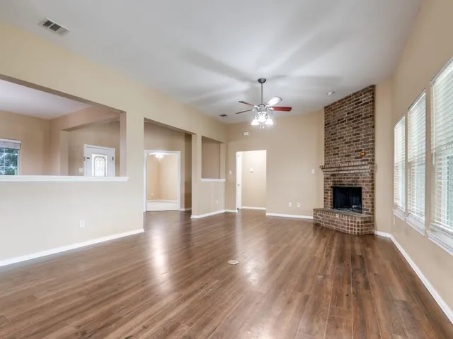 a view of an empty room with wooden floor fireplace and a window