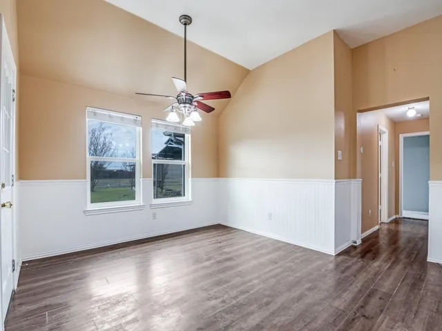 a view of an empty room with wooden floor fireplace and a window