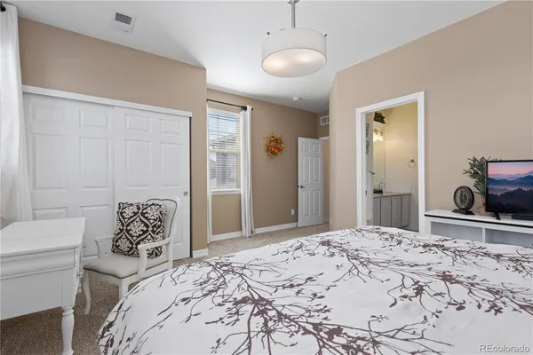 a bedroom with a bed and a large mirror on dresser next to a window