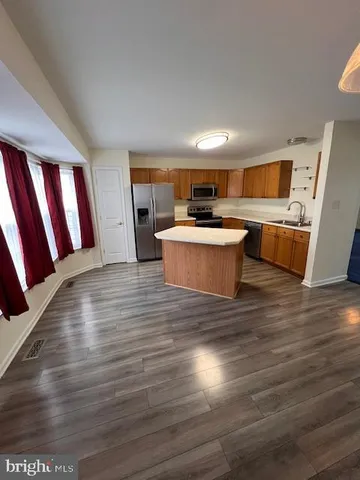 a kitchen with stainless steel appliances a sink a stove top oven a refrigerator and cabinets