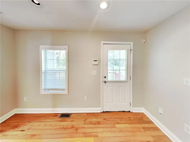 an empty room with wooden floor and windows