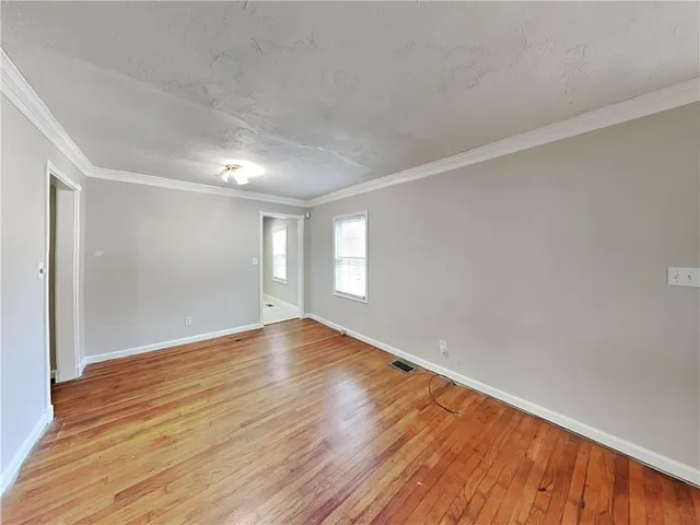 a view of an empty room with wooden floor and window