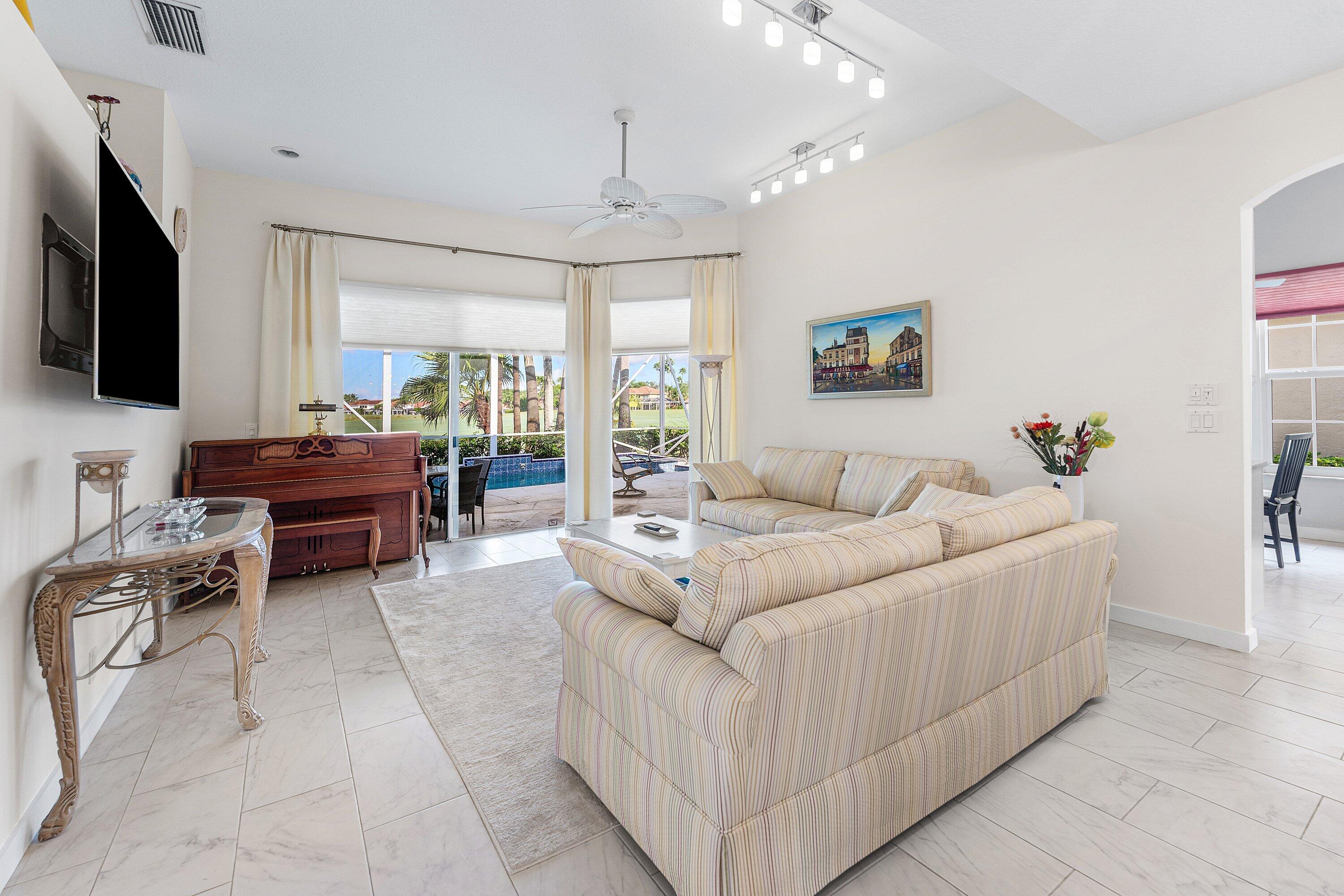 8217 Quail Meadow Way West Palm Beach, FL 33412 - Photo 9 of 38 a living room with furniture a flat screen tv and a chandelier