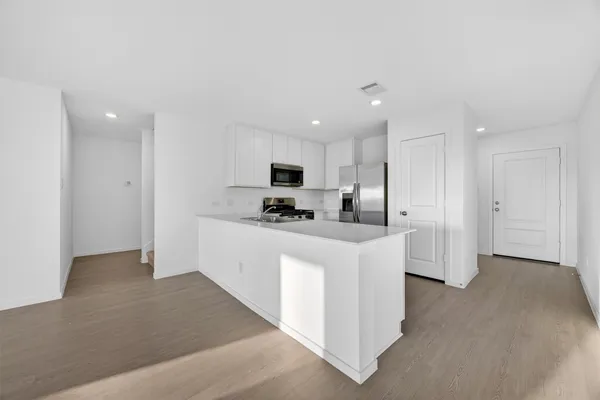 a kitchen with stainless steel appliances kitchen island sink refrigerator and cabinets