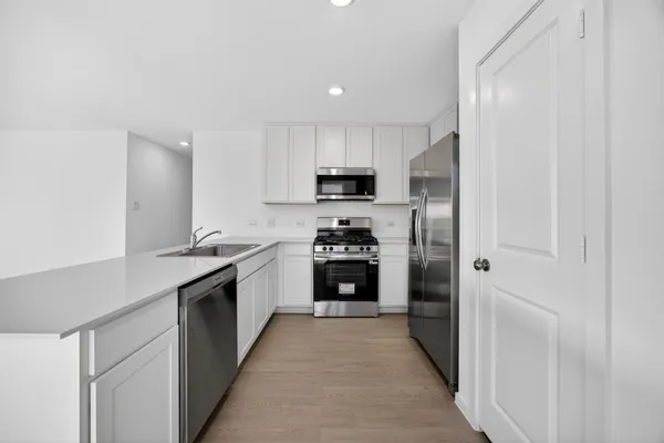 a kitchen with granite countertop a refrigerator and a stove top oven