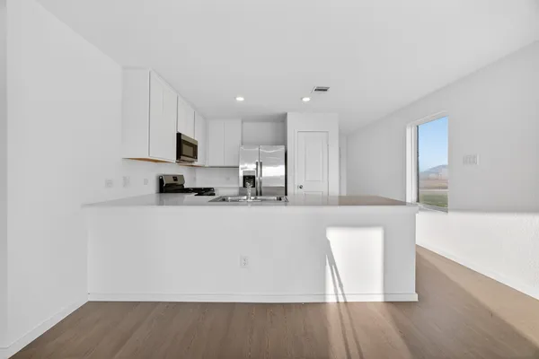 a large white kitchen with wooden floors and a fireplace