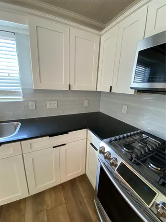 a kitchen with white cabinets and appliances