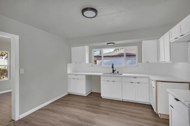 a kitchen with white cabinets and wooden floor