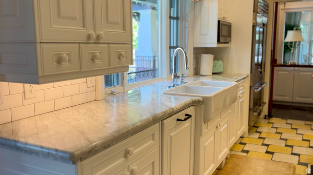 426 West Center Street Parowan, UT 84761 - Photo 22 of 107 Kitchen featuring white cabinetry, a double basin farmhouse sink, light-toned countertop, subway tile backsplash, and built-in stainless steel appliances