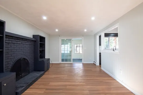 a view of empty room with wooden floor and fireplace