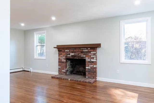an empty room with wooden floor fireplace and windows