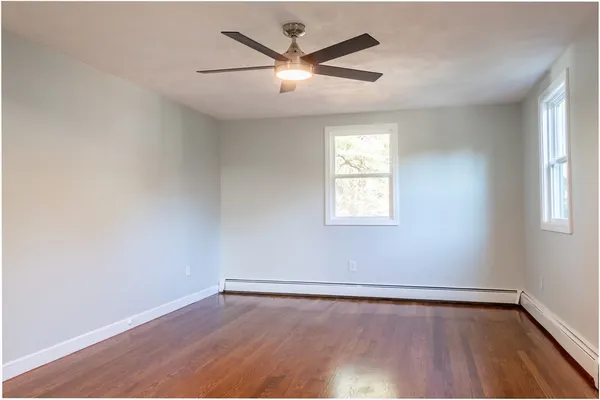 an empty room with wooden floor and windows