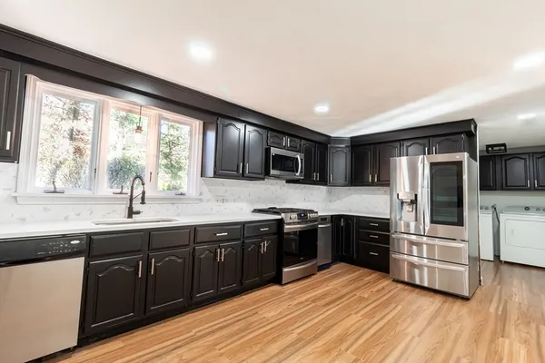 a kitchen with stainless steel appliances granite countertop a sink stove and refrigerator