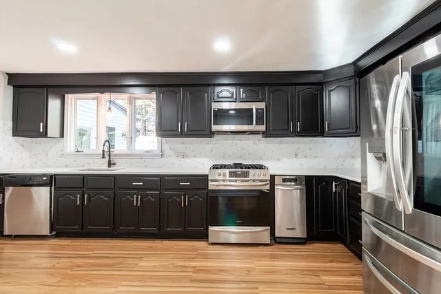 a kitchen with stainless steel appliances granite countertop a stove a sink and a microwave