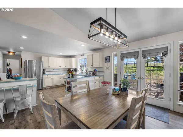 a kitchen with stainless steel appliances kitchen island granite countertop a table chairs and white cabinets