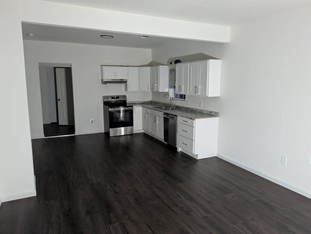 205 North Wood Street Cleburne, TX 76033 - Photo 4 of 15 a kitchen with stainless steel appliances wooden floors and view living room