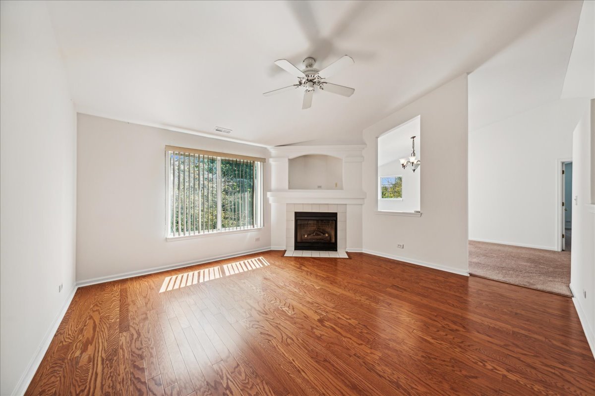 973 Park Hill Circle, Unit 973 Aurora, IL 60502 - Photo 4 of 17 an empty room with wooden floor fireplace and windows