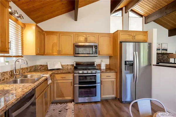 a kitchen with stainless steel appliances granite countertop a refrigerator a stove top oven a sink and dishwasher