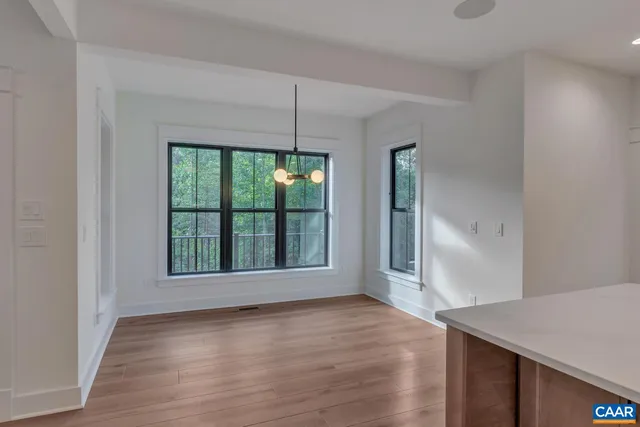 a view of an empty room with wooden floor fireplace and a window