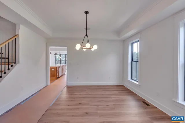 a view of a room with wooden floor chandelier and windows