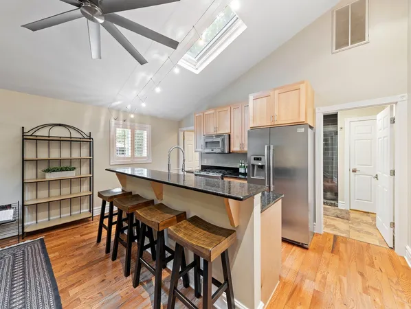 a kitchen with stainless steel appliances kitchen island granite countertop a dining table chairs and granite counter tops