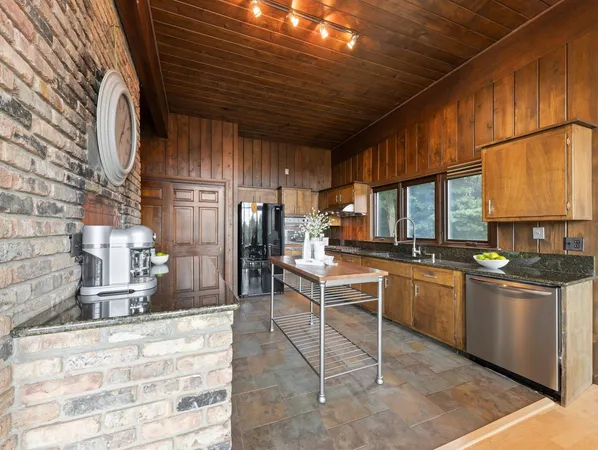 a kitchen with stainless steel appliances granite countertop a sink a stove a refrigerator cabinets and a dining table