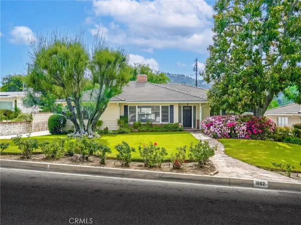 a front view of a house with a yard and potted plants