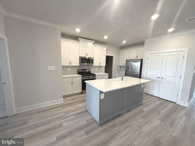 a large kitchen with stainless steel appliances granite countertop a large counter top and wooden floors