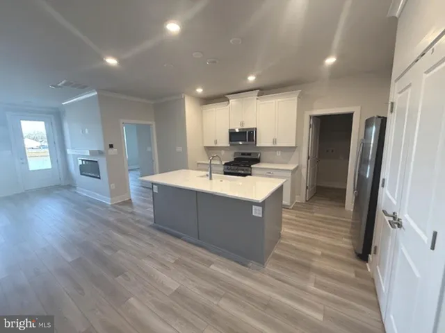 a large white kitchen with wooden floors and stainless steel appliances