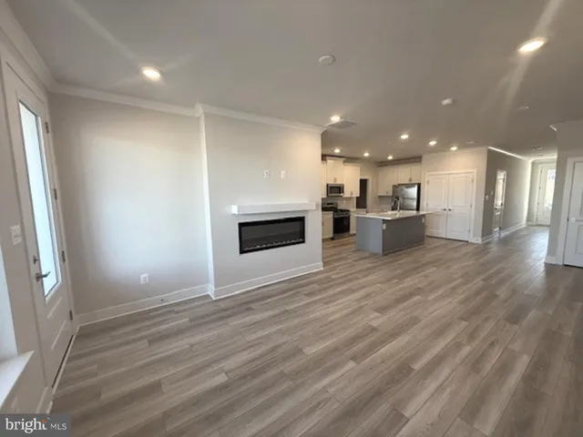 an empty room with wooden floor and a kitchen