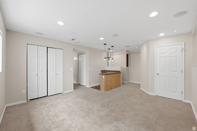 2575 Athena Drive Magna, UT 84044 - Photo 16 of 23 Spacious room featuring neutral carpet, recessed lighting, a built-in bar with pendant lights, and multiple bi-fold closet doors