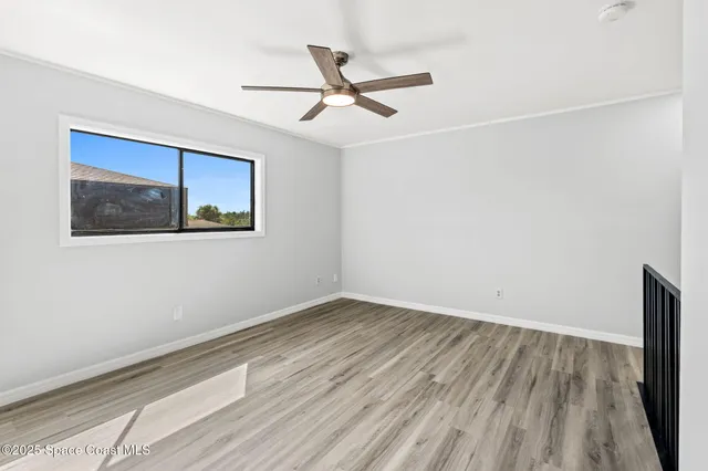 an empty room with wooden floor and ceiling fan