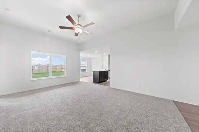 an empty room with windows and ceiling fan view